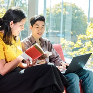 Two students accessing book and online materials while studying